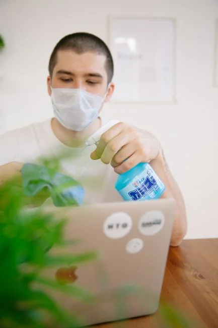 Un agent de nettoyage portant une combinaison de protection et des gants aspire un salon moderne.